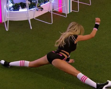 A woman doing a split with a fist raised in the air.