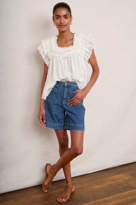 Model wearing blue denim shorts and a white broderie anglaise top