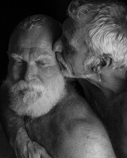 A black and white portrait of two men in their 60s sharing a tender embrace