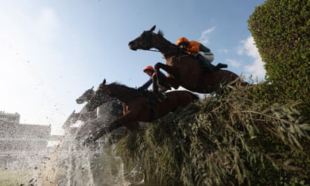 Horses clear the water jump in the Grand National.