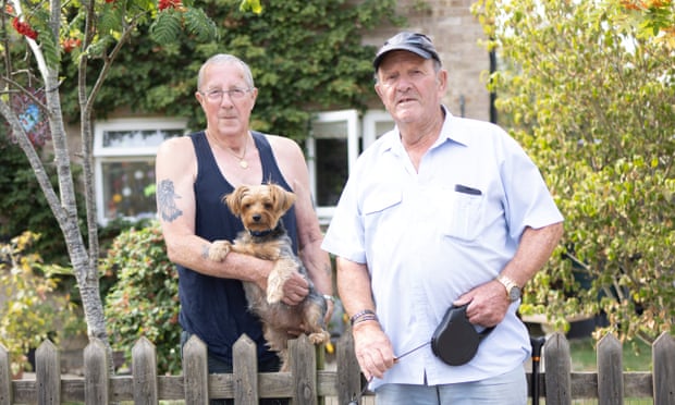 Geoffrey Trigg (left) and Harold Fuller, watching drinking water from another burst pipe run down their street.