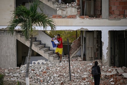A man carries belongings out of a damaged building following an earthquake in Catia La Mar, La Guaira state, 30km north-west of Caracas, on 25 June.