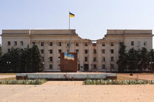 The Kherson city administrative building with a Ukrainian flag and a big hole in the roof