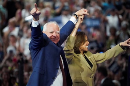 Two politicians hold arms aloft in front of large crowd.