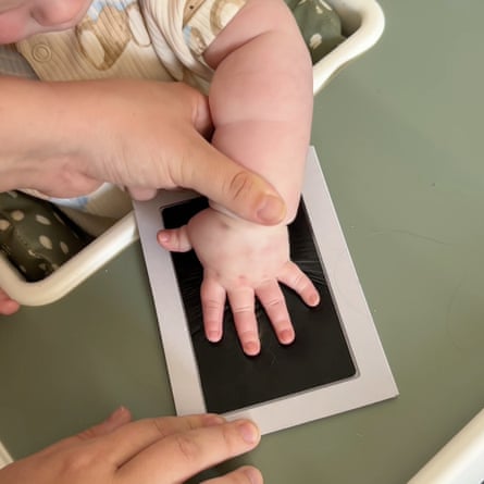 An adult presses a baby’s hand on to an ink pad