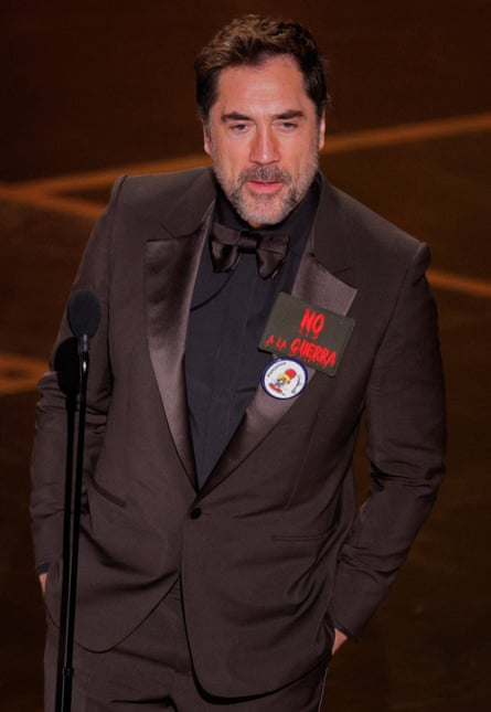 Bardem with large lapel badge reading ‘No a la Guerra’ in bright red
