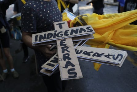 A person holds cardboard crosses that read ‘indigenous land’ during a protest against budget cuts on public education by President Jair Bolsonaro’s government.