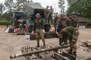 Soldiers dressed in camo uniform talking and loading a rocket launcher