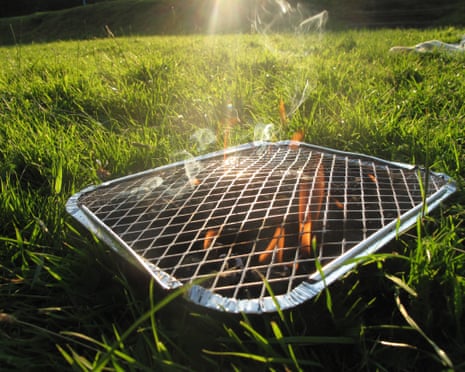 A lit disposable barbecue on grass