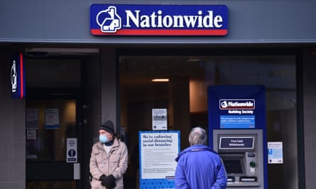 A man wearing a face mask stands outside a Nationwide branch