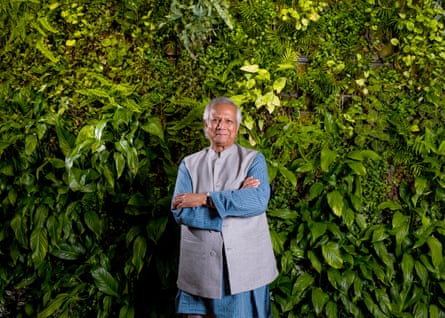 Portrait of Muhammad Yunus standing in front of a hedge