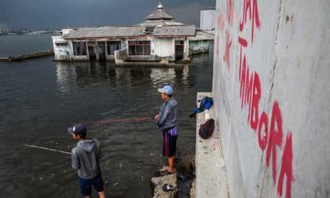 Men fish near an abandoned mosque outside a seawall in Muara Baru, North Jakarta., Indonesia. Jakarta is sinking as a result of massive groundwater extraction. Photograph by Kemal Jufri for The Guardian
