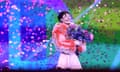 Nemo holds flowers on stage as confetti is released above them