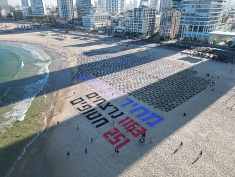 A display of human figures at a beach near large Hebrew letters that spell 'Total Failure'.