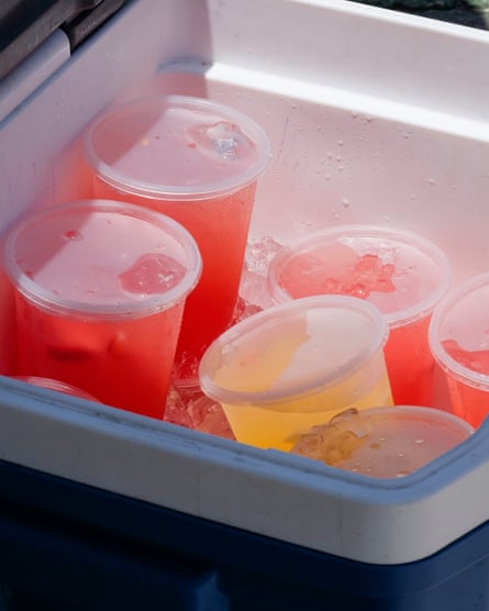 a cooler filled with cups of pink and yellow juice