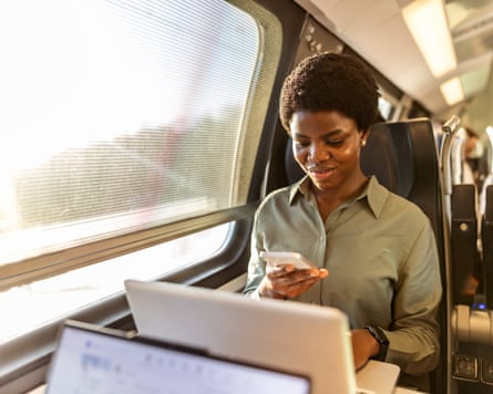 A multitasking with a smartphone and laptop during her commute on a train