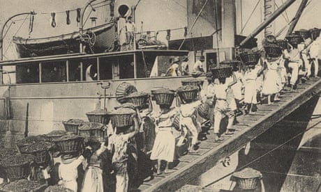 Black and white image of men and women carrying baskets boarding a coaling ship