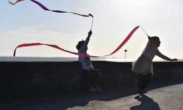 Children playing with streamers by a sea wall