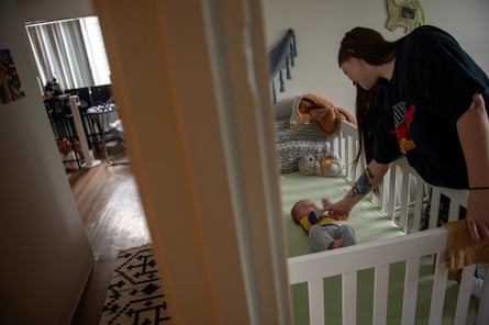 A woman puts her baby into his crib