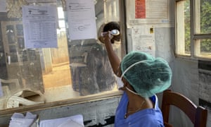 A medical worker checks a person’s temperature at the Matanda Hospital in Butembo, where the first case of Ebola died, in the North Kivu province of Congo.