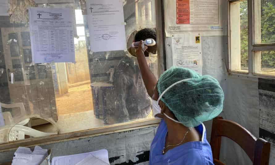A medical worker checks a person’s temperature at the Matanda Hospital in Butembo, where the first case of Ebola died, in the North Kivu province of Congo.