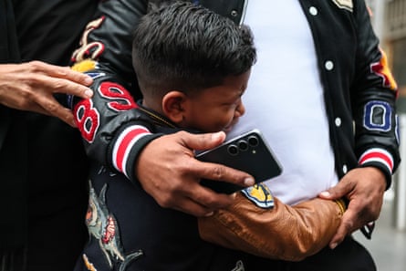 A child of about 7 or 8 years old with his arm’s around his father’s waist, and his father’s arms holding his.