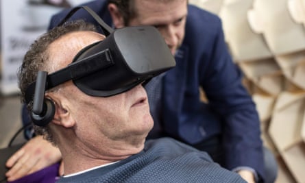 Dutch designer Alexander Bannink explains how the “Sarco” euthanasia pod works to a man via virtual reality goggles.