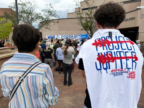 a person wears a shirt with the words 'project Jupiter' crossed out