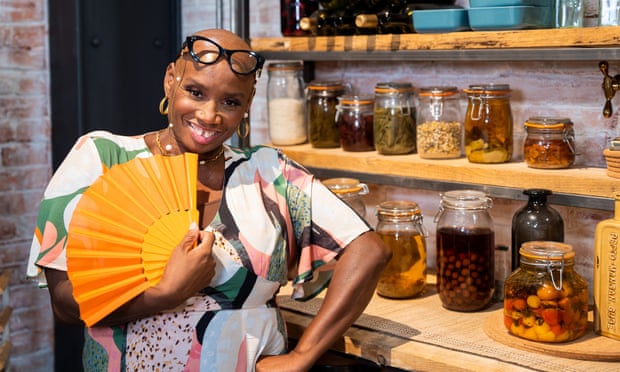 Andi Oliver, in front of shelves of mason jars, smiling and holding an open paper fan