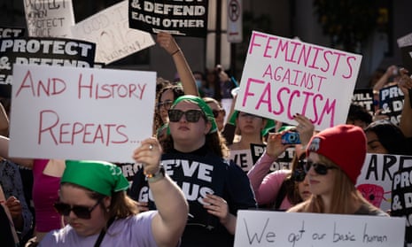 Pro-choice protesters carrying signs reading FEMINISTS AGAINST FASCISM and DEFEND EACH OTHER.