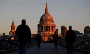 People walk towards St Paul's Cathedral during sunrise in central London