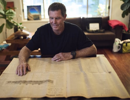 Andrew Rogers with an old newspaper spread out in front of him at a table in his home