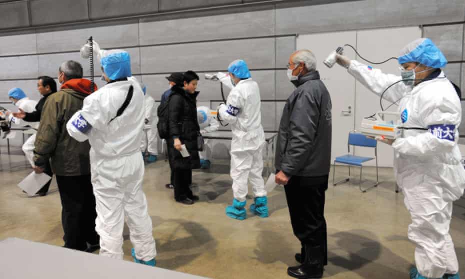 Japanese medical personnel check people for radiation exposure