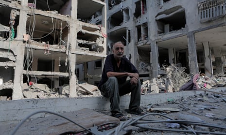 A man sits among buildings destroyed in Israeli air strikes in Gaza.