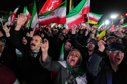 Supporters of the Iranian regime chant slogans and wave flags