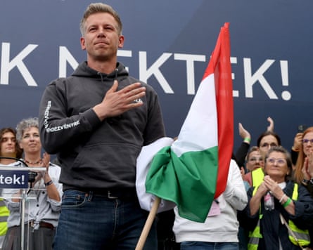 Péter Magyar in front of a crowd holding a Hungarian flag.