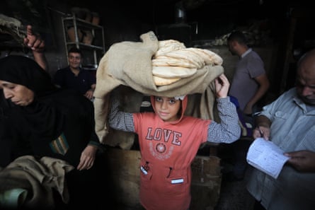 Палестинская девушка несет на голове связку буханок хлеба, завернутую в сумку.