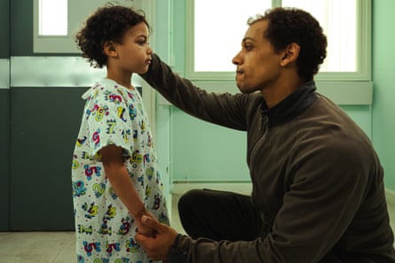A small boy in a hospital gown with a man kneeling in front of him