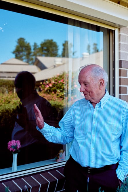 Andrew waves to a neighbour through a window.
