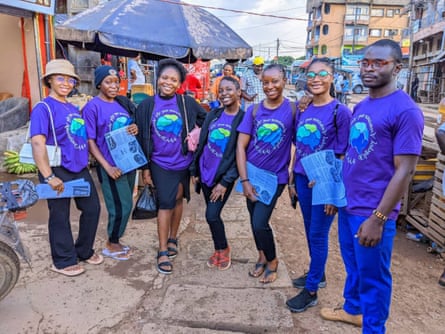 A group of seven volunteers in indigo T-shirts with epilepsy awareness slogan stand in a street with pamphlets