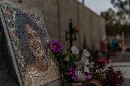 A mosaic portrait of a smiling young woman on a grave with flowers