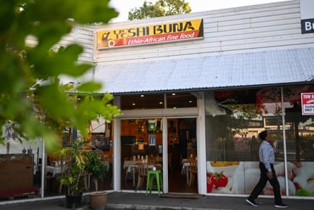 Exterior of Yeshi Buna, an Ethiopiain restaurant with large glass windows and a white corrugated roof.