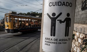 A tram passes by a sign warning of armed robberies.