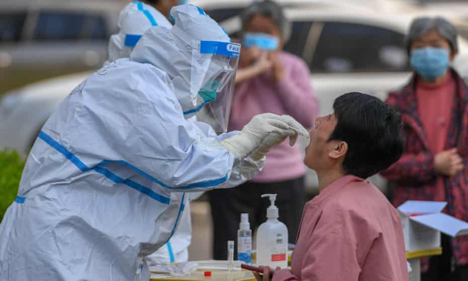 A medical worker collects a throat swab at a residential community in Shulan, north-east China’s Jilin Province, where an outbreak has been reported.