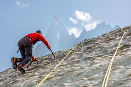 Person climbing up an ice wall with crampons, with a massive mountain peak above them