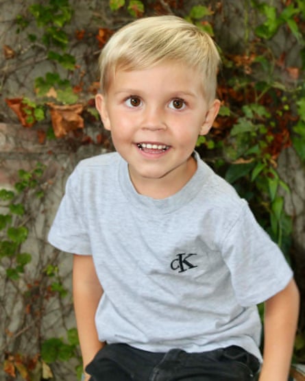Boy smiles in front of wall of vines and leaves