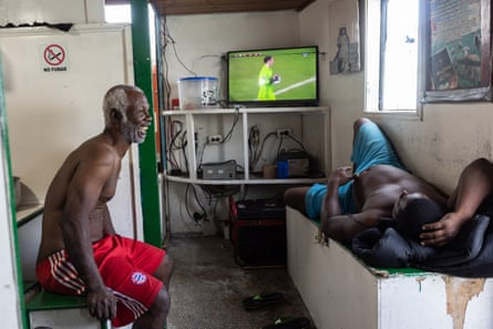 An old man laughs as he talks to a young man lying on a bench