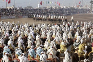 A crowd of costumed men on horseback take part in the Moussem festival
