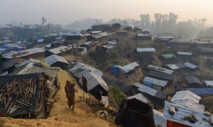 A female Rohingya refugee walks with a child in the refugee camp