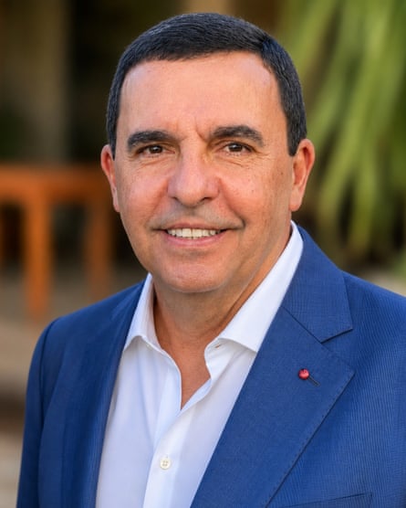 Carlos de Almeida Baptista Júnior, smiling slightly in a blue jacket and white shirt